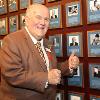 Harold Lederman proudly poses in front of the Hall of Fame Wall.